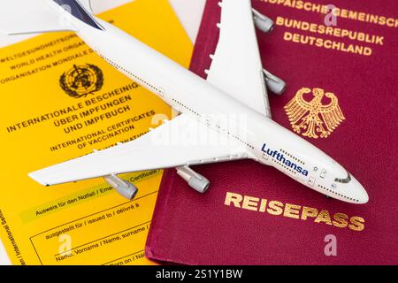 Flugreise mit Reisepass und Impfbuch ein Modellflugzeug der Lufthansa steht auf einem Deutschen Reisepass und einem Impfbuch *** Flugreise mit Passp Stockfoto