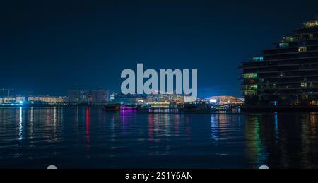 Yas Island von Al Raha in Abu Dhabi, VAE, mit seiner beleuchteten Skyline und reflektierenden Lichtern an der ruhigen Uferpromenade. Die Szene capt Stockfoto
