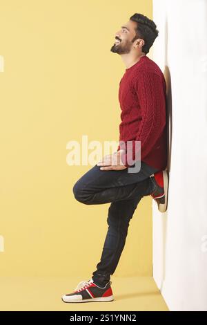 Ein asiatisches männliches Modell, das in rotem Pullover auf gelbem Hintergrund im Stil posiert Stockfoto