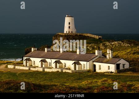 TWR Mawr Lighthouse & Pilots Cottages beleuchtet von der aufgehenden Sonne an einem stürmischen Morgen auf Llanddwyn Island in Anglesey, Nordwales. Stockfoto