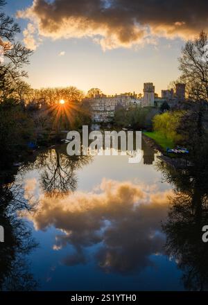 Die untergehende Sonne scheint durch die Bäume am Ufer des Flusses Avon bei Warwick Castle. Stockfoto