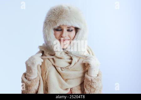 Lächelnde moderne 40-jährige Frau im Wintermantel und Pelzhut isoliert auf weiß in weißen Handschuhen. Stockfoto