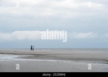 Paare genießen die Ruhe und das Wunder eines frühen Morgenspaziergangs entlang der Küste von Jacksonville Beach, Florida. (USA) Stockfoto