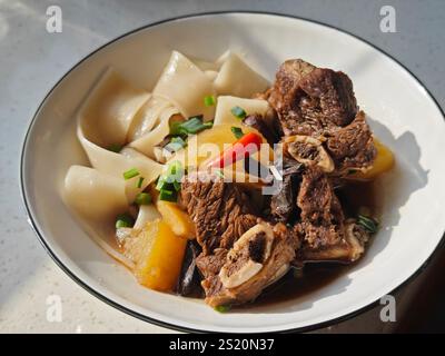 Frischer Rindereintopf mit Kartoffeln auf den breiten Nudeln in der Schüssel zum Essen Stockfoto