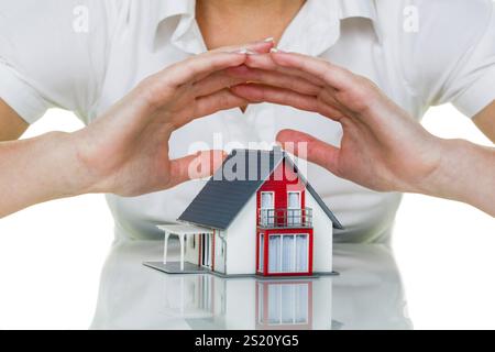 Eine Frau beschützt Ihr Haus und Ihr Zuhause. Gute Versicherungen und seriöse Finanzierungen sorgen für ein beruhigendes Gefühl Stockfoto
