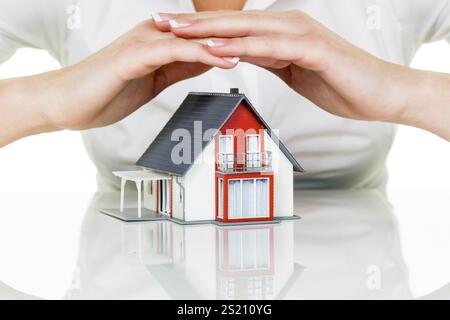 Eine Frau beschützt Ihr Haus und Ihr Zuhause. Gute Versicherungen und seriöse Finanzierungen sorgen für ein beruhigendes Gefühl Stockfoto