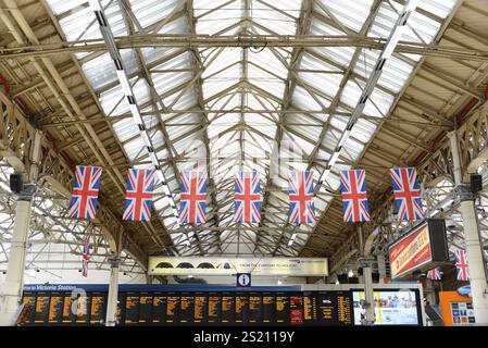 London Victoria Station, Bahnhof, London, Region London, Ein Bahnhof voller britischer Flaggen und Informationstafeln an der Decke des Stockfoto