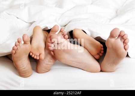 Die Fußsohlen einer Familie im Bett unter der Decke. Österreich Stockfoto