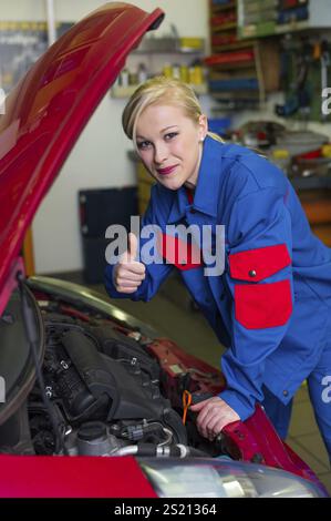 Eine junge Frau, die als Mechanikerin in einer Autowerkstatt arbeitet. Seltene Berufe für die Frau. Das Auto wird in einer Garage repariert Stockfoto