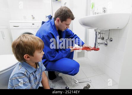 Ein Klempner repariert ein kaputtes Waschbecken in einem Bad in Österreich Stockfoto