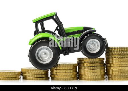 Die Landwirte in der Landwirtschaft müssen mit steigenden Kosten rechnen. Höhere Preise für Futtermittel, Düngemittel und Pflanzen. Traktor mit Münzen Stockfoto