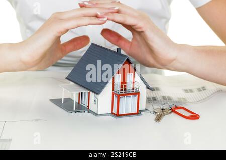 Eine Frau beschützt Ihr Haus und Ihr Zuhause. Gute Versicherungen und seriöse Finanzierungen sorgen für ein beruhigendes Gefühl Stockfoto