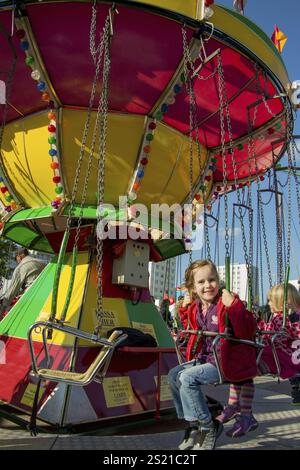 Kind fährt auf einer Messe ein Kettenkarussell und hat Spaß in Österreich Stockfoto