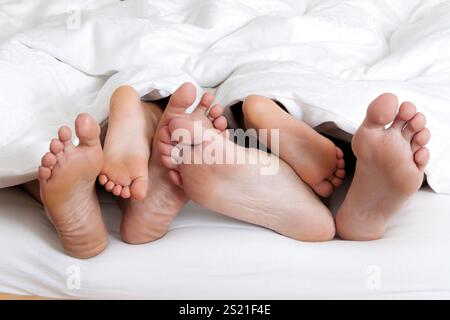 Die Fußsohlen einer Familie im Bett unter der Decke. Österreich Stockfoto