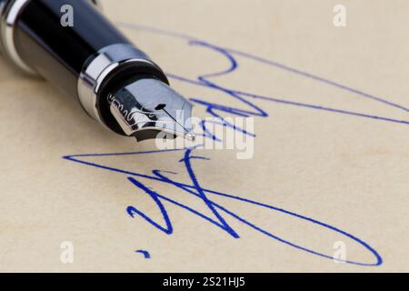 Ein Füllfederhalter und eine Unterschrift auf gelbem Papier. Symbolisiert die Unterzeichnung von Verträgen. Österreich Stockfoto