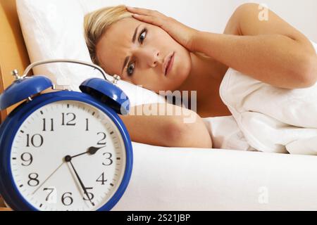 Schlaflosigkeit mit Uhr in der Nacht. Frau kann nicht schlafen, Uhr mit Schlaf in der Nacht. Frau kann nicht schlafen. Österreich Stockfoto