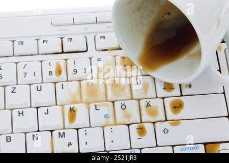 Eine Tasse Kaffee ist auf einer Computertastatur verschüttet. Versicherungsschaden, Tasse Kaffee ist auf eine Computertastatur verschüttet. Schadenversicherung. Österreich Stockfoto
