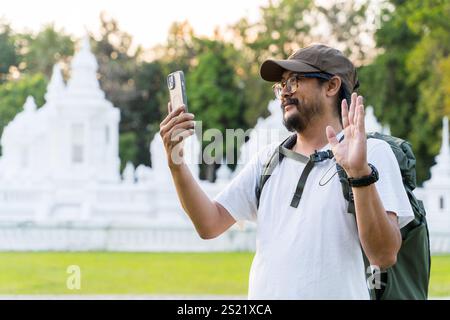 Glücklicher Tourist, der während seiner Reise ein Handy benutzt, während er Videoanrufe tätigt. Happy man Blogger Caucasian Guy männlicher Influencer Blogger fröhlich Smile Touris Stockfoto
