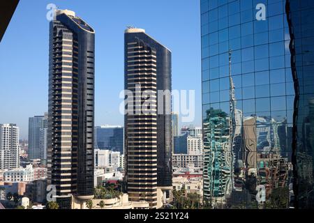 San Diego, Kalifornien, USA. Dezember 2024. Ein atemberaubender Blick auf die Innenstadt von San Diego mit zwei ikonischen schwarz-beigen zylindrischen Türmen, die vor dem Hintergrund moderner urbaner Architektur eingerahmt sind. Die rechte Seite des Fotos zeigt die reflektierende Fassade eines nahe gelegenen Glashochhauses und erzeugt verzerrte, künstlerische Reflexionen der umliegenden Gebäude. Dieses Bild aus einem hohen Blickwinkel zeigt das dynamische Zusammenspiel zwischen architektonischen Stilen und dem hellen, klaren kalifornischen Himmel und unterstreicht die lebendige und sich entwickelnde Skyline der Stadt. (Foto: © Ian L. Sitren/ZUMA Press Stockfoto