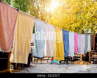 Bunte Handtücher hängen Wäsche an der Wäscheleine im Garten im Herbst. Wäscheleine mit frisch gewaschener mehrfarbiger Kleidung im Freien A Stockfoto