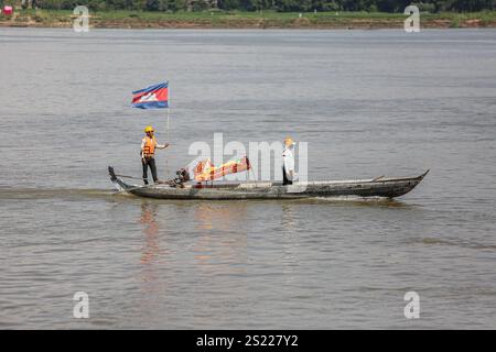 Fluss Mekong, Kambodscha. 5. Januar 2025: Khmer-Arbeiter mit Schutzhüten und Schwimmwesten beobachten den Mekong, einen der längsten Flüsse Asiens, in kleinen Booten unter der Flagge des Königreichs Kambodscha. Auf kambodschanischer Seite befinden sich die meisten Flussufer noch in ihrem natürlichen Zustand, was sie anfällig für Erosion aufgrund von Wasserflusskontrolle (chinesische Dämme) oder Sandbaggern macht. Quelle: Kevin Izorce/Alamy Live News Stockfoto