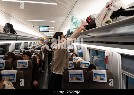Hangzhou, China, 5. Januar 2025. Passagiere stellen ihr Gepäck am 5. Januar 2025 in Hangzhou, Provinz Zhejiang in China, auf die Gepäckablage eines Zuges am Bahnhof Hangzhou West. Mit der Aufnahme von Hochgeschwindigkeitszügen zwischen dem Bahnhof Hangzhou West und dem Bahnhof Hong Kong West Kowloon können Passagiere aus Hangzhou nun ihr Ziel Hongkong innerhalb eines Tages erreichen. Quelle: Wu Junyi/China News Service/Alamy Live News Stockfoto