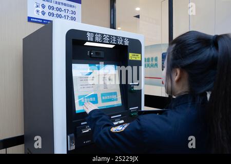Hangzhou, China, 5. Januar 2025. Ein Mitarbeiter demonstriert am 5. Januar 2025 in Hangzhou, Provinz Zhejiang in China, den Einsatz eines intelligenten Reiseverzeichnungsgeräts am Bahnhof Hangzhou West. Mit der Aufnahme von Hochgeschwindigkeitszügen zwischen dem Bahnhof Hangzhou West und dem Bahnhof Hong Kong West Kowloon können Passagiere aus Hangzhou nun ihr Ziel Hongkong innerhalb eines Tages erreichen. Quelle: Wu Junyi/China News Service/Alamy Live News Stockfoto