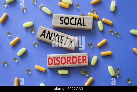 Symbol der sozialen Angststörung. Konzeptworte soziale Angststörung auf Holzblöcken. Schöner lila Hintergrund mit Pillen. Gesundheit und Soziales Stockfoto