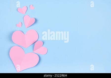 Einfarbiger hellblauer Hintergrund mit rosafarbener Papierherzen-Applikation für Valentinstag-Banner Stockfoto