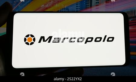 In dieser Abbildung hält eine Person ein Handy mit dem Logo des brasilianischen Automobilkonzerns Marcopolo SA auf dem Bildschirm vor der Website. Stockfoto