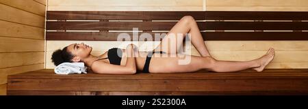 Eine junge, schicke Frau entspannt sich bequem auf einer Holzbank in einem Spa. Stockfoto