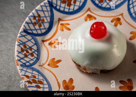 Nahaufnahme einer traditionellen sizilianischen Cassata-Torte, dekoriert mit Ricotta, kandierten Früchten und einer Kirsche darauf, serviert auf einem wunderschön dekorierten Teller. Stockfoto