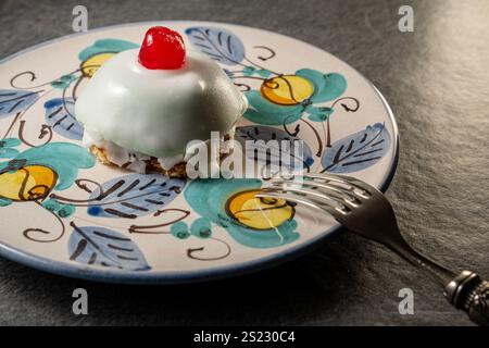 Nahaufnahme einer traditionellen sizilianischen Cassata-Torte, dekoriert mit Ricotta, kandierten Früchten und einer Kirsche darauf, serviert auf einem wunderschön dekorierten Teller. Stockfoto