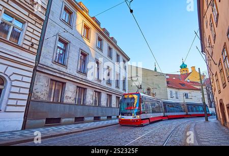 Die moderne rote Straßenbahn auf der schmalen Letenska Straße, gesäumt von schäbigen Häusern, Mala Strana, Prag, Tschechien Stockfoto