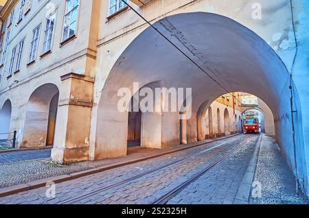 Die alte rote Straßenbahn, die durch die gewölbte Passage in der Letenska Straße in Mala Strana, Prag, Tschechien fährt Stockfoto