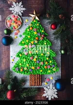 Blick von oben auf den Weihnachtsbaumkuchen, der mit Süßigkeiten auf dem Holztisch dekoriert ist. Stockfoto
