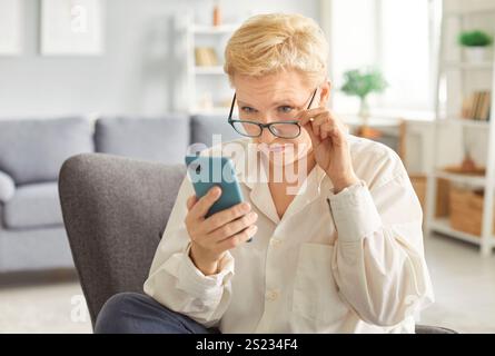 Ältere Dame, die Anwendungen auf dem Smartphone nutzt, alte reife Frau, die im Messenger plaudert Stockfoto