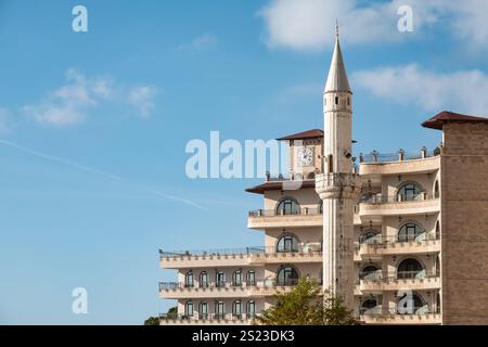 Aus der Vogelperspektive auf die Stadt Kruja Albania, mit Außenansicht des Hotels und dem Moscheeturm-Minarett vor blauem Himmel. Moderne Gebäudearchitektur in Kruje. Trav Stockfoto