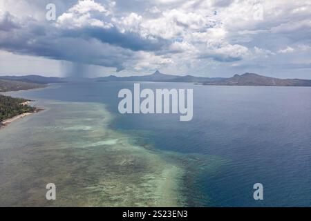 Aus der Vogelperspektive auf die Lagune von Mayotte mit sichtbaren Korallenriffflächen und der kleinen Insel Sada im Vordergrund. Die Aufnahme erfasst den Kontrast zwischen dem Stockfoto