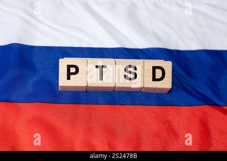PTSD Akronym auf Holzblöcken und die russische Flagge. Posttraumatische Belastungsstörung im Zusammenhang mit Krieg. Stockfoto
