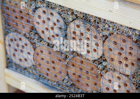 Ein dekoratives Insektenhotel bietet eine Vielzahl von Holzstämmen und Hohlrohren, die im Garten Nützlinge schützen. Stockfoto