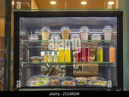 Frisch gepresster Saft und Smoothies gesundes Essen Salatschalen und Getränke im Regal im Kühlschrank Stockfoto