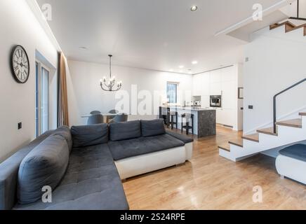 Modernes, offenes Wohnzimmer und Küche mit modernen Möbeln, einer Treppe und elegantem Dekor in sanften neutralen Farben für einen stilvollen und stilvollen Stil Stockfoto