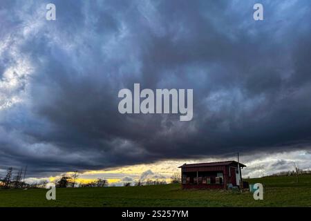 Dunkle Wolken am Himmel wie hier in Siegen-Oberschelden am spaeten späten Nachmittag. Es ist sehr windig bis stuermig stürmig. Im Vordergrund steht eine Hütte. Winter im Siegerland am 06.01.2025 in Siegen/Deutschland. Stockfoto