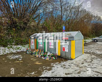 Viele leere Flaschen und Gläser neben den Behältern, die nach den Feiertagen zur getrennten Sammlung von Glas überfüllt waren. Januar 2025. Uberlingen, Deutschland Stockfoto