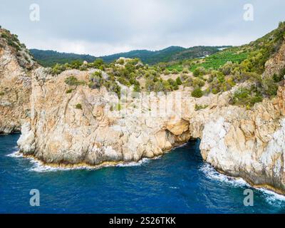 Ein atemberaubender Blick auf zerklüftete Klippen und üppiges Grün, das auf das pulsierende blaue Meer trifft. Fängt die Schönheit und Ruhe der Küstenlandschaften ein und bietet einen Stockfoto