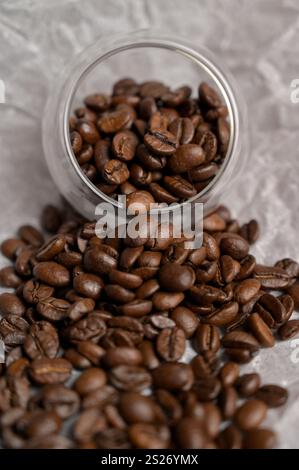 Frische aromatisch geröstete Kaffeebohnen aus einem kleinen Glas auf Bastelpapier. Arabica- und Robusta-Mischung Stockfoto