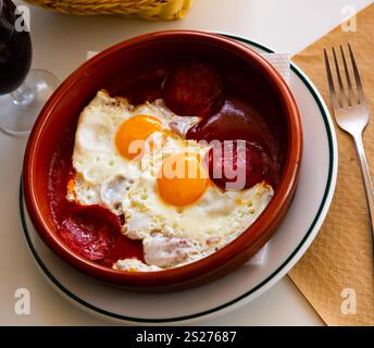 Beliebtes spanisches Gericht, Spiegeleier mit Chorizo-Würstchen und Tomatenpaste auf Teller Stockfoto
