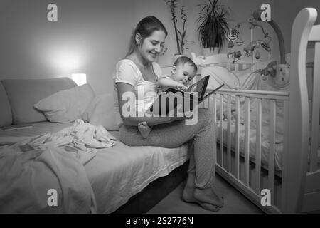 Schwarz / weiß Bild der jungen Mutter Lesebuch zu ihrem Baby Sohn vor dem Schlafengehen Stockfoto