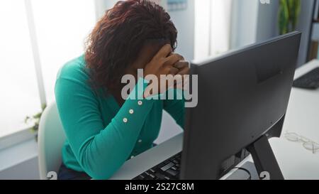 Frau, die Stress bei der Arbeit erlebt, mit dem Kopf nach unten in einer Büroumgebung Stockfoto